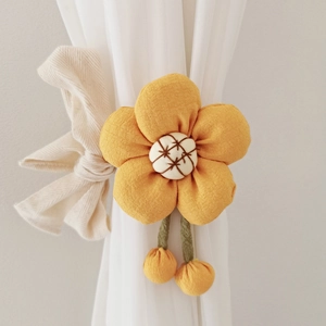 Close-up of yellow flower curtain tieback with white embroidery and beige fabric bow