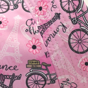 Close-up of geometric pink Paris theme fabric with fine white stitching on bucket hat