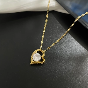 Macro di una collana a cuore dorata con cristallo centrale e catena a onde d'acqua