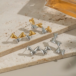 Close-up of gold and silver heart-shaped stainless steel drop earrings on stone steps