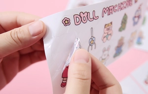 Close-up of peeling a cute transparent cartoon sticker showing adhesive quality and detail