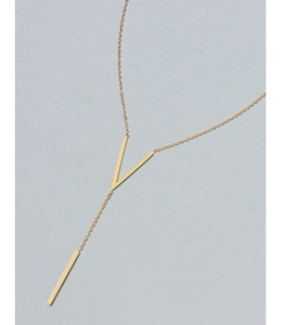 Detailed view of a gold V-shaped Y-necklace with bar pendant on light blue texture