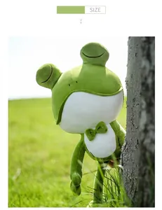 Adorable green frog plush toy standing in a sunny grassy field by a tree trunk detail view