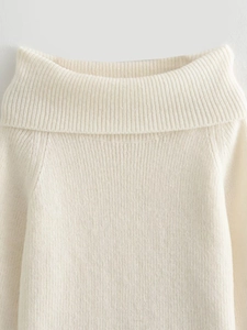 Gros plan d'un pull crème à épaules dénudées montrant la texture délicate de la maille