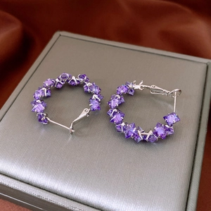 Detailed view of silver hoop earrings featuring geometric purple zircon stones on display