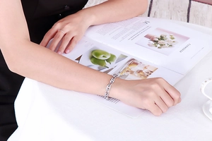 Detailed view of a silver pig-nose chain bracelet on wrist with a lifestyle background