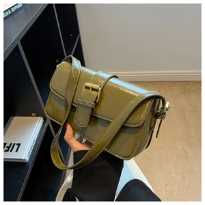 Detail of vintage avocado green waxed leather texture and bronze buckle on small square bag