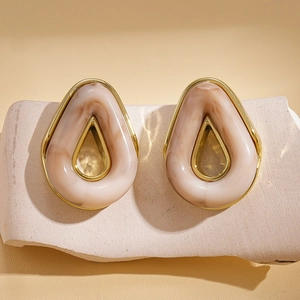 Close-up of teardrop resin earrings with gold frame on stone base for women