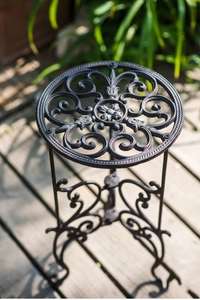Détail d'un support de plante en fonte noire avec motifs floraux ajourés élégants