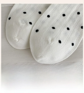 Detailed macro view of seamless white cotton socks featuring stylish black polka dots