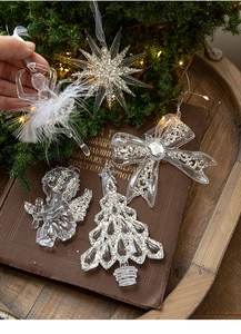 Clear acrylic Christmas ornaments with silver glitter on vintage books and pine needles