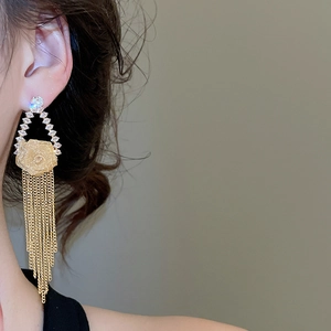 Close-up of gold-plated flower tassel earring with zircons on a model's ear