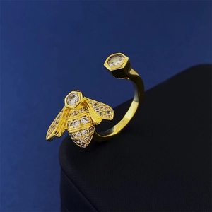 Close-up of golden bee ring with sparkling zircons on wings and hexagonal honeycomb detail