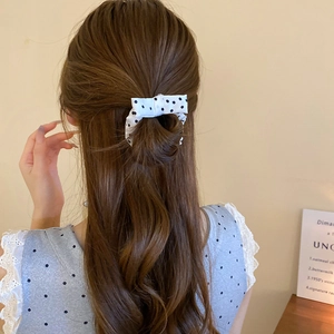 Rear view of cream scrunchie with black polka dots and soft bow on woman's hair
