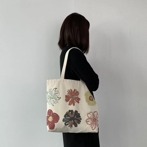 Floral canvas tote bag with hand-drawn colorful sunflowers worn on the shoulder