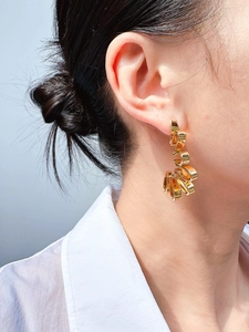 Close-up of golden architectural folding metal earrings with abstract twisted ribbon design