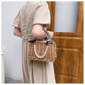 Detail of hand-woven straw bag with pearl accents and black-white checkered silk scarf