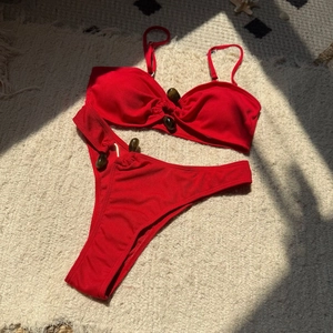 Close-up of red ribbed bikini fabric with brown beaded accents on plush rug background