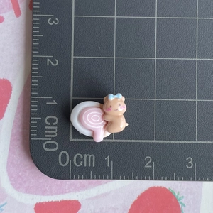 Miniature resin bear charm with blue bow showing small 1.5cm size on ruler scale