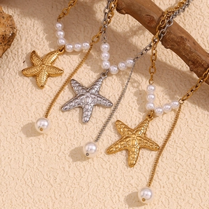 Detailed view of starfish pendant necklaces with pearls hanging on a wooden branch