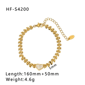 Dettaglio del bracciale dorato con cuore in madreperla e targhetta K18 incisa con cura
