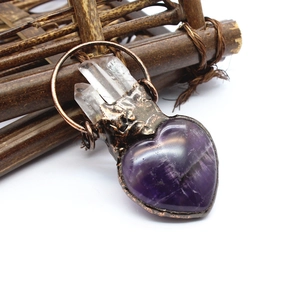 Macro shot of heart-shaped amethyst pendant with crystal points on copper base