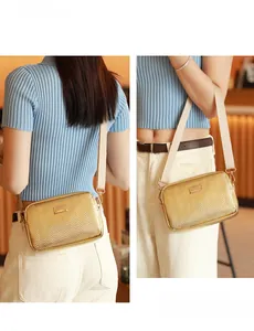 Detail of gold crossbody camera bag with chevron quilting and wide adjustable strap