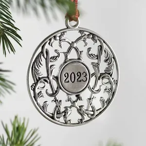 Close-up of vintage metal Christmas ornament with 2023 engraving on a tree
