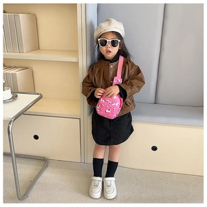 Close-up of a pink unicorn crossbody bag on a child model wearing a stylish brown PU jacket