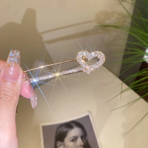 Close-up of heart-shaped safety pin brooch with crystals and gold-plated finish