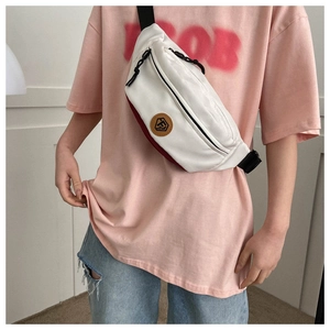 Detail of white and red oxford crossbody bag showing front zipper and adjustable strap