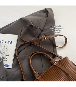 Close-up of pleated texture on a brown shoulder bag with a thin adjustable strap