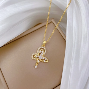 Detailed close-up of golden hollow butterfly pendant with zircon inlay on white silk