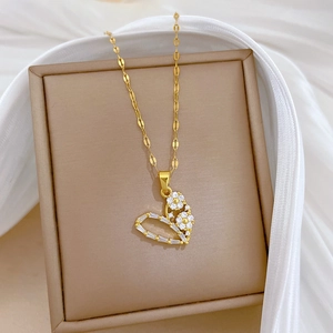 Close-up of golden hollow heart necklace with zircon inlay on a beige display box
