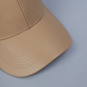 Detailed macro view of khaki PU leather baseball cap with lychee texture and fine stitching