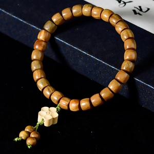 Détail de perles en bois de santal avec pendentif lotus sculpté et cordon vert