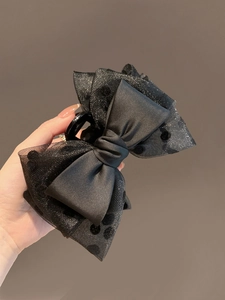 Detail of a black satin and polka dot organza bow hair claw clip held by hand