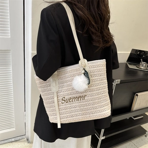 Beige straw tote bag with Summer embroidery and white decorative charms on a shoulder strap
