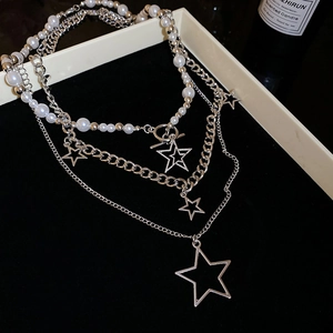 Detailed close-up of multi-layer silver necklace with star pendants and pearls on a display