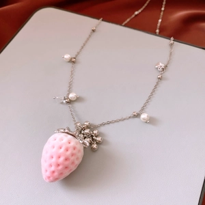 Macro detail of flocking texture pink strawberry pendant with silver chain and pearls