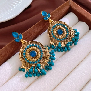 Vue détaillée de boucles d'oreilles vintage en or avec pierres bleues et pompons