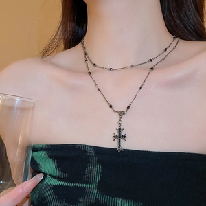 Detail of gothic double-layer cross necklace with black crystals on collarbone
