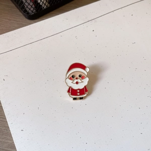 Detail of Santa Claus enamel brooch with vibrant red and white glaze and gold metal edges