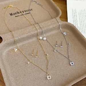 Gold and silver necklace and earring sets with pearls and zircon pendants on a tray