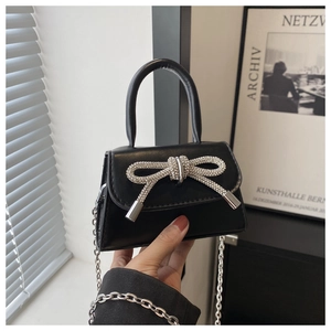Detail of black mini crossbody bag featuring a sparkling rhinestone bow and silver chain