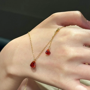 Detailed view of red heart crystal pendants on a delicate gold-plated chain necklace