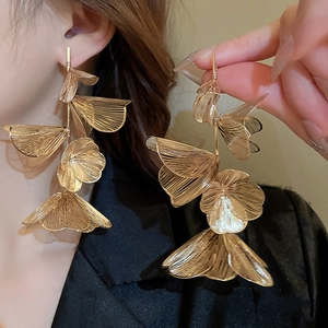 Macro shot of long gold flower tassel earrings with intricate brushed metal texture