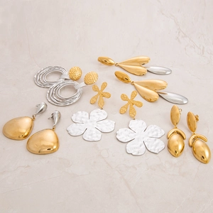 Flat lay of diverse gold and silver floral and teardrop earrings on marble background