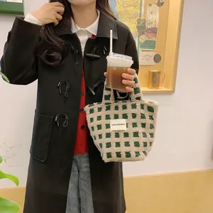 Close-up of green and white checkerboard sherpa tote bag with minimal brand label