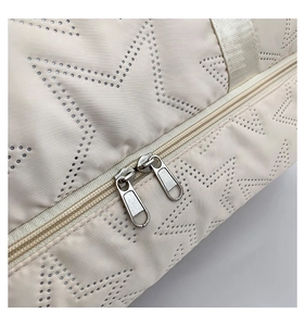 Detail of star-patterned beige gym bag showing durable nylon fabric and dual metal zippers